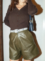 Perfect sustainable spring outfit. Upcycled leather shorts - high-waisted, wide-leg, and short-length. Styled on brunette model with brown knit and snakeskin belt.